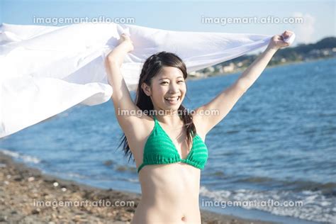 海辺で布を広げる水着姿の女性の写真素材 [24019349] イメージマート