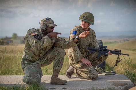 A U.S. soldier and a British paratrooper discusses marksmanship at a multinational military ...