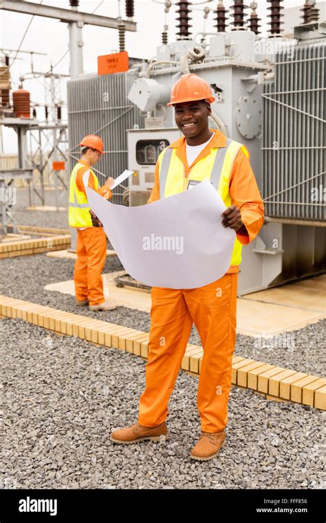 Portrait Of Handsome African Electric Engineer With Blueprint At