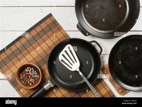 Several Empty Cast Iron Frying Pans On A White Wooden Background View