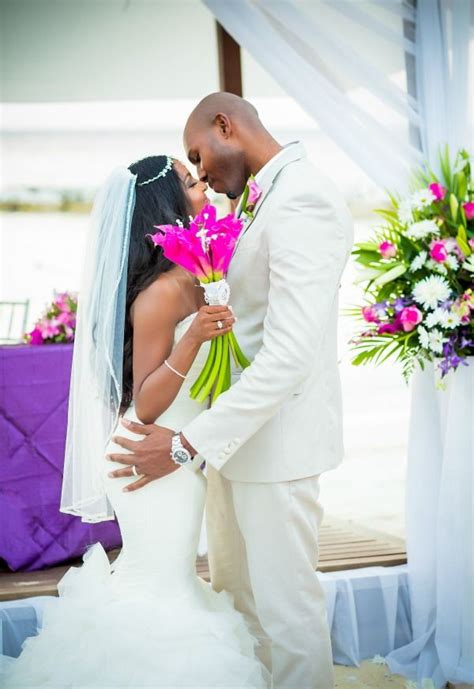 A Bride And Groom Kissing In Front Of An Altar With Pink Flowers On It