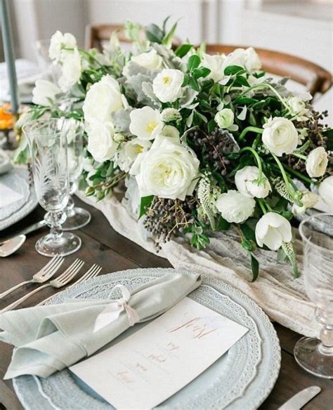 The Table Is Set With White Flowers And Place Settings