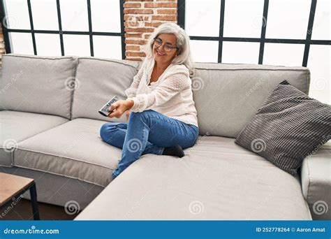 Middle Age Woman Watching Movie Sitting On Sofa At Home Stock Photo