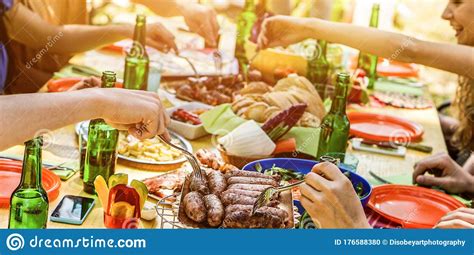 Happy Friends Eating Barbecue Meat Outdoor In City Park On Summer Time