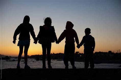 "Silhouette Of Four Kids Holding Hands On The Coast At Sunset" by ...