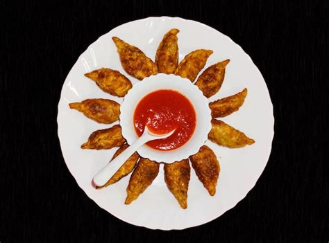 Premium Photo | Momos fried in white plate with red sauce