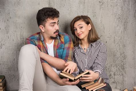 Jeune Couple Assis Sur Le Sol Et Lisant Un Livre Photo Gratuite