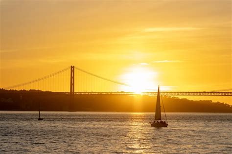 Pôr do sol laranja brilhante sobre o rio e um barco à vela flutuando