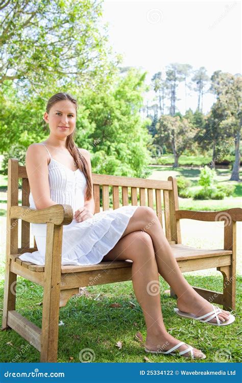 Vrouw Met Haar Benen Gekruiste Zitting Op Een Parkbank Stock Foto