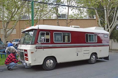 An Old Bus Is Parked On The Side Of The Road With Two People Standing