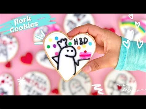 A Hand Holding A Decorated Heart Shaped Cookie In Front Of Some Cookies