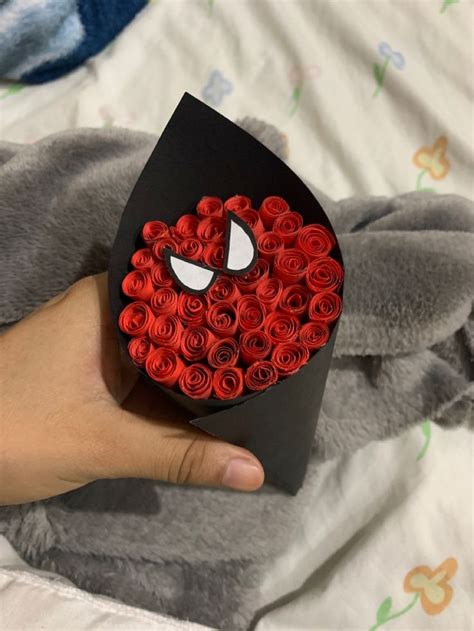 A Hand Holding A Black Box With Red Roses In The Shape Of A Spider Man