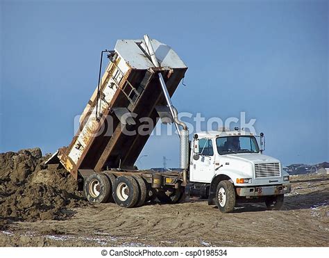 Tandem dump truck. A truck unloading some dirt at a construction site ...