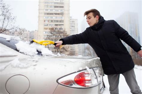 Premium Photo Guy Cleans The Snow With A Brush From The Car A Man