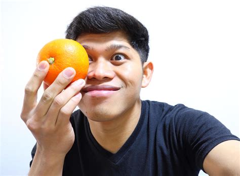 Attractive Asian Man Eating Oranges Isolated On White Background