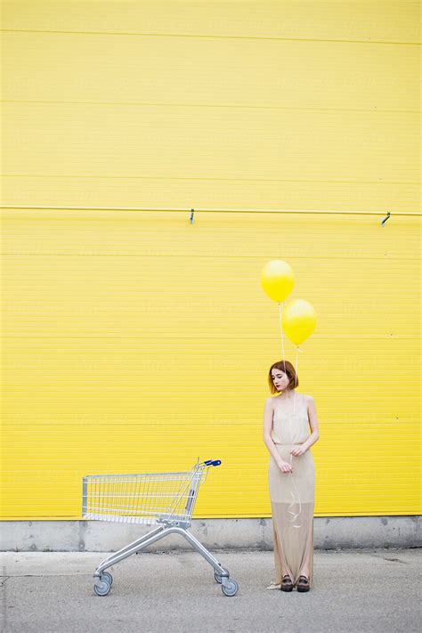 Young Woman Standing Against A Yellow Wall And Holding The Balloon By Stocksy Contributor