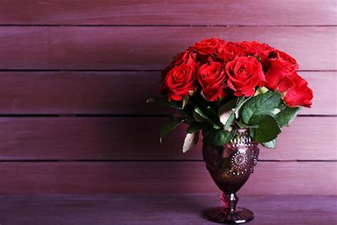 Premium Photo Bouquet Of Red Roses In Glass Vase On Wooden Background