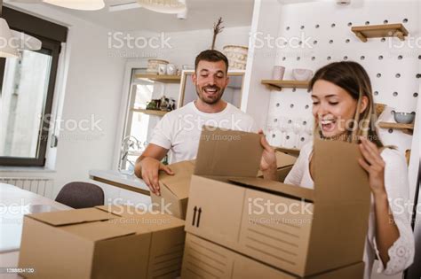 Young Couple Carrying Big Cardboard Box At New Homemoving House Stock