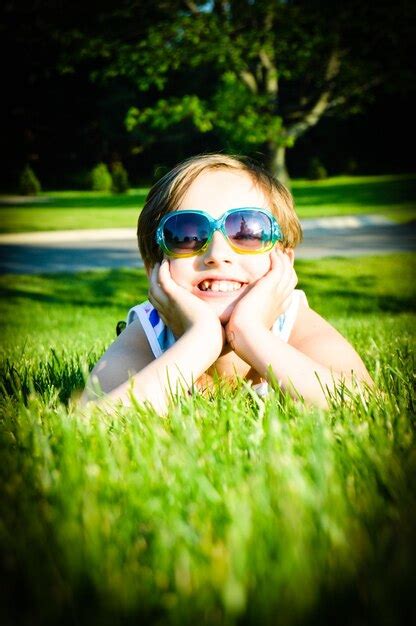 Premium Photo Portrait Of Cute Happy Girl With Sunglasses Lying On Grass