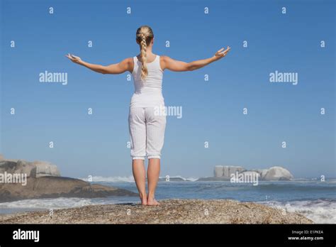 Blonde Woman Standing On Beach On Rock With Arms Out Stock Photo Alamy