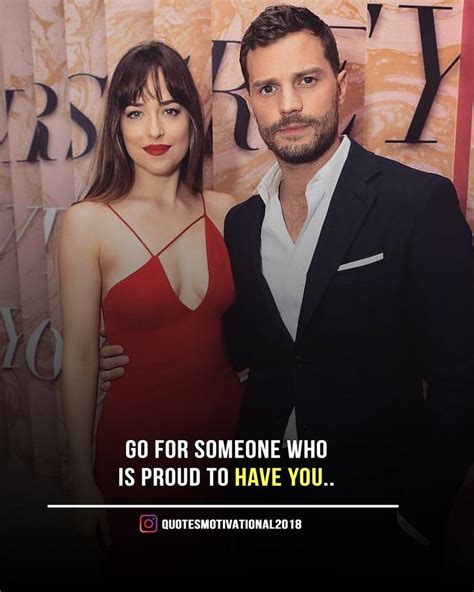 A Man And Woman Standing Next To Each Other In Front Of A Sign That