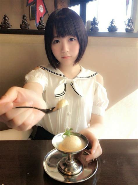 A Woman Sitting At A Table With A Spoon In Her Hand And Food On The Plate