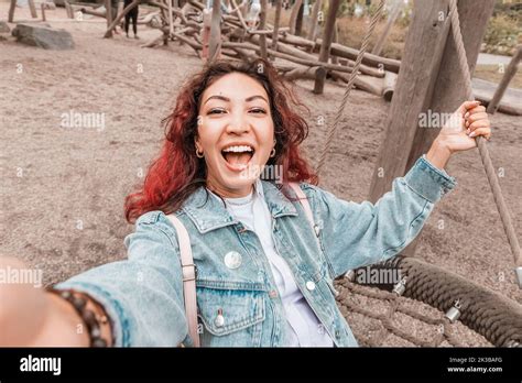 Happy girl has fallen into childhood, has fun and rides on a swing on the playground for ...