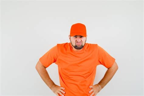 Free Photo Delivery Man In Orange T Shirt Cap Holding Hands On Waist