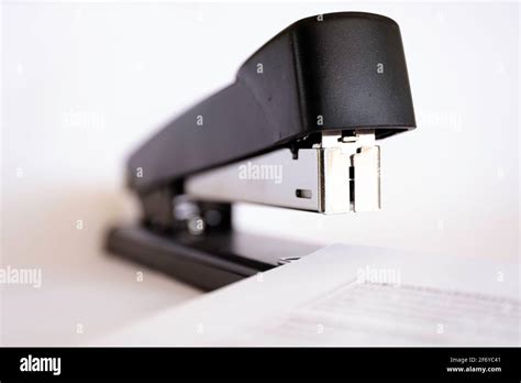 Close Up Front View Of A Black Stapler Stapling Several Sheets Of Paper