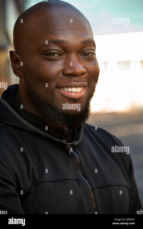 Portrait of young man with beard and a bald head standing outside looking at camera Stock Photo ...