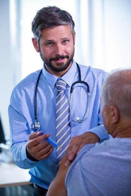 Doutor masculino que dá uma injeção a um paciente no hospital Foto Grátis