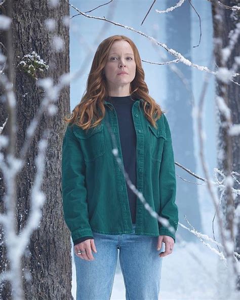 A Woman Standing Next To A Tree In The Snow With Her Hands On Her Hips