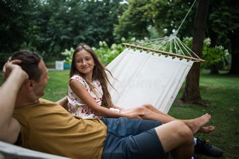 Father And Teen Daughter Relaxing On A Hammock In The Woods Happy