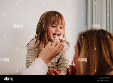 Female Doctor Checking For Sore Throat Of Girl Patient Girl Child