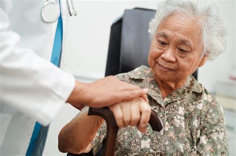 El médico ayuda a una anciana asiática con discapacidad a una paciente