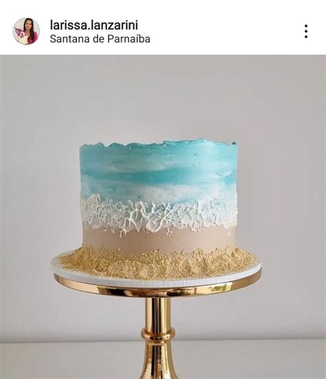 A Blue And White Cake Sitting On Top Of A Gold Plate With Sand Around It