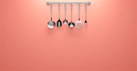 stainless steel cooking utensils hanging  pink wall  stock photo