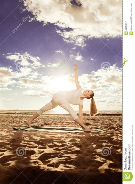 Young Beautiful Slim Woman Practices Yoga On The Beach At Sunrise Yoga At Sunset Stock Image