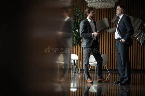 Two Businessmen Deep In Discussion Together While Standing In Modern