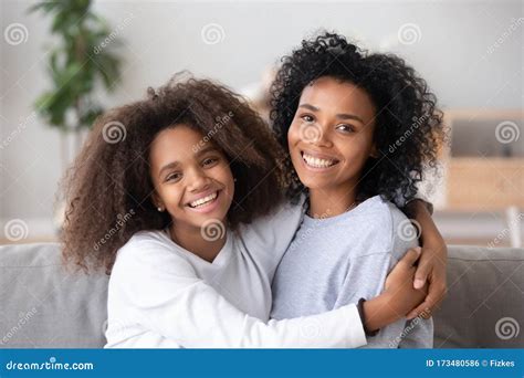 Happy African Mother And Teen Daughter Embracing Looking At Camera