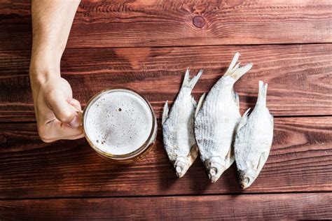 Mano Con El Vidrio De Cerveza Y Los Pescados Secados Imagen De Archivo