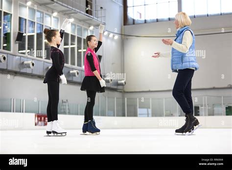 Full Length Portrait Of Two Girls Figure Skating On Ice Rink With