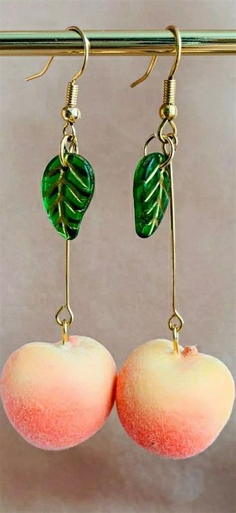 Two Peaches With Green Leaves Hanging From Hooks