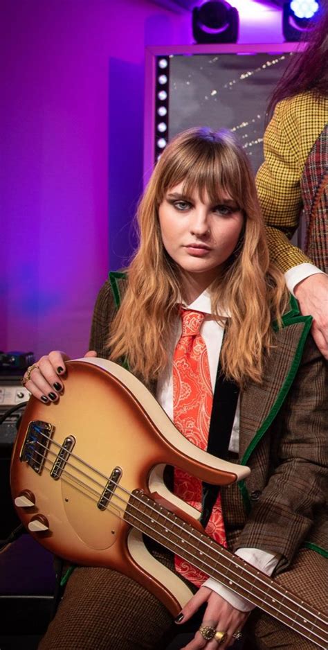 A Woman In A Suit And Tie Holding A Guitar