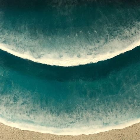 An Aerial View Of The Ocean Waves And Sand On A Beach With Blue Green Water