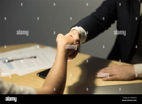 Businessman In Suit Greeting Female Coworker Over Desk In Office After