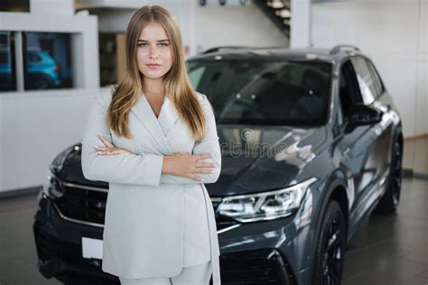 Portrait of Salesperson in Car Showroom. Attractive Young Woman Stend ...