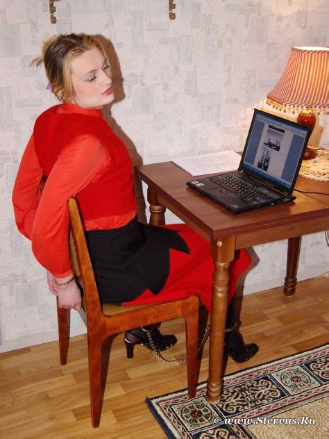 Woman On Chair Hands Cuffed Behind Back And Ankles Shackled Patiently