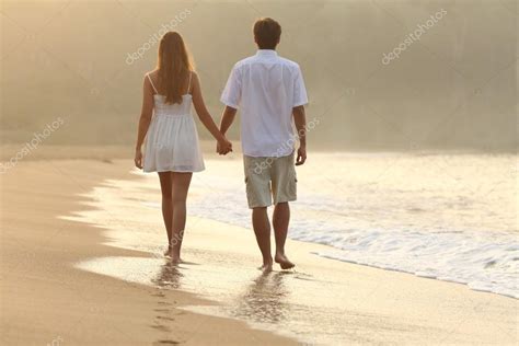 Couple Walking And Holding Hands On The Sand Of A Beach Stock Photo