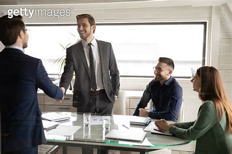 Smiling Businessmen Shake Hands Get Acquainted At Meeting 1307791619